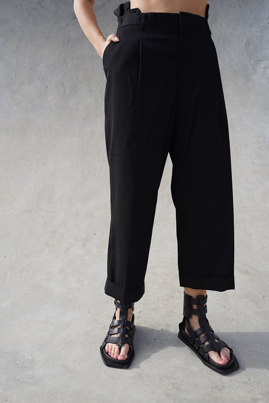 Rear view of the black tapered pants, showcasing the fit and drape of the fabric