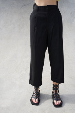 Elegant black cropped pants with unique pleated design, showcased on a model